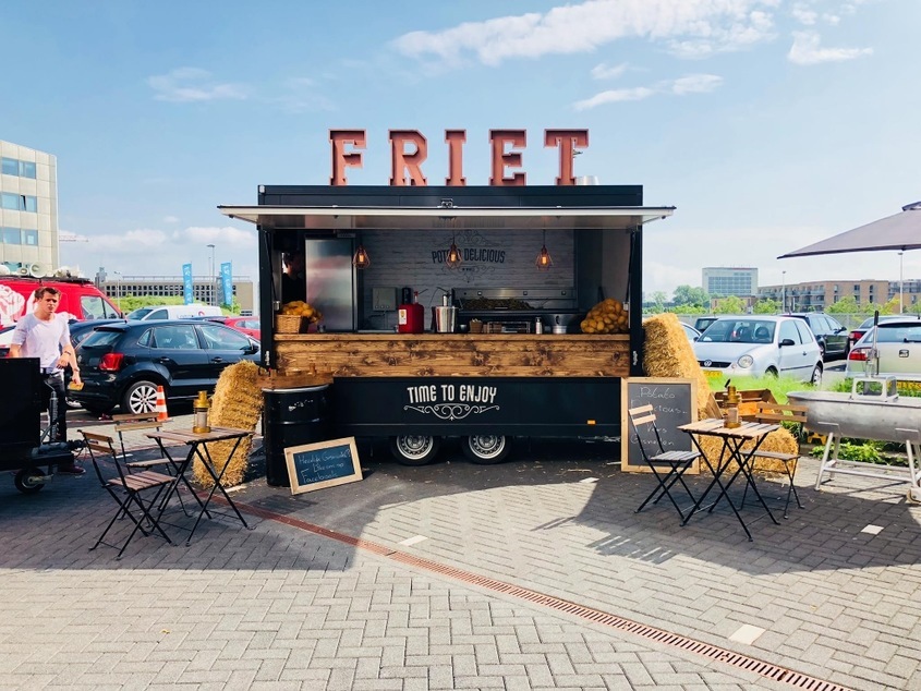 Onze zwarte frietwagen met groot FRIET-bord en houten toonbank